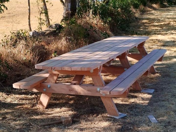 Grande table de pique-nique en Douglas installée dans un pré arboré